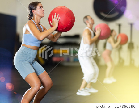 Young woman training with ball in gym 117860590