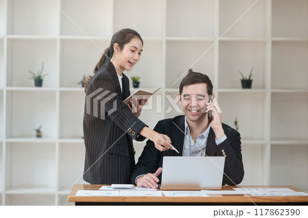 A woman and a man are talking on their cell phones in a room with a lot of shelv 117862390