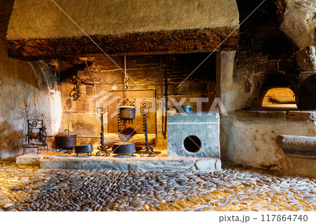 Fireplace in a castle with cooking utensils. Interior of the medieval Gruyeres castle in Gruyeres town, Switzerland 117864740