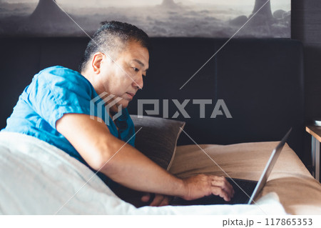 ベッドでパソコンを使う男性 117865353