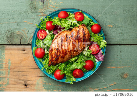 Grilled chicken breast ( fillet ) with lattuce salad and cherry tomatoes . Top view 117869016
