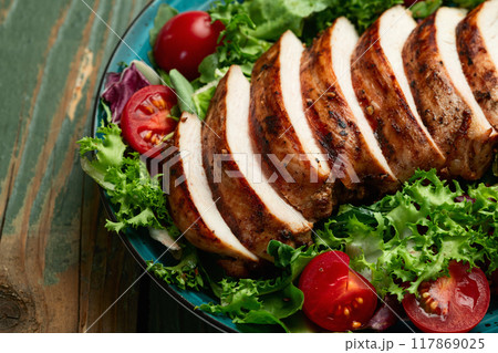 Grilled chicken breast ( fillet ) with lattuce salad and cherry tomatoes . Top view Grilled chicken breast ( fillet ) with lattuce salad and cherry tomatoes . Top view 117869025