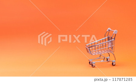 Supermarket concept. An empty supermarket trolley isolated on an orange background. Free space for your text, copy space Supermarket concept. An empty supermarket trolley isolated on an orange background. Free space for your text, copy space 117871285