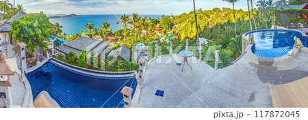 View over an infinity pool on a slope above a tropical beach View over an infinity pool on a slope above a tropical beach 117872045