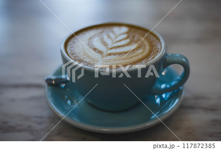 Delight in a beautifully crafted coffee with intricate latte art served in a cozy cafe ambiance on a tranquil morning Delight in a beautifully crafted coffee with intricate latte art served in a cozy cafe ambiance on a tranquil morning 117872385
