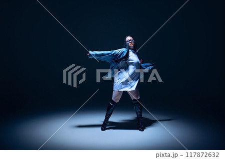 Creative blend of hip-hop and high heels dance styles. Talented and artistic young woman performing against black studio background 117872632
