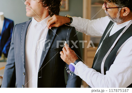 Professional Indian stylist marking suit while customer standing still 117875187