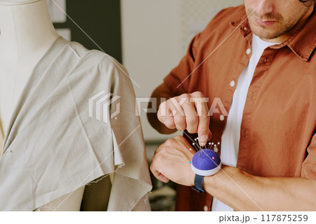Unrecognizable tailor choosing needle to do darts on mannequin Unrecognizable tailor choosing needle to do darts on mannequin 117875259