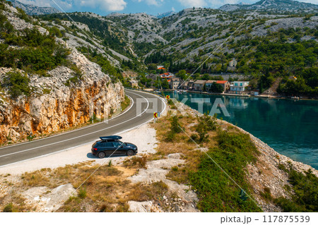 Car with a roof box stands on the cliff of lagoon, aerial view Car with a roof box stands on the cliff of lagoon, aerial view 117875539