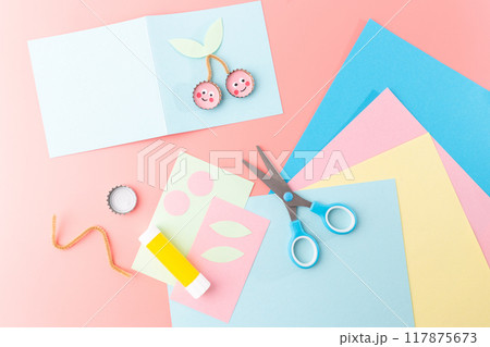 Bottle cap cherries with pink centers, white dots, and green paper leaves. Artistic and playful DIY craft ideas for homemade postcards and engaging kids activities, DIY 117875673