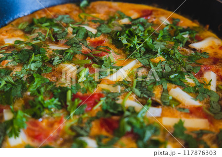 Deliciously vibrant omelette with fresh herbs and vegetables cooking in a skillet on a sunny morning Deliciously vibrant omelette with fresh herbs and vegetables cooking in a skillet on a sunny morning 117876303