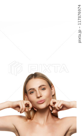 Vertical portrait of attractive young woman with both clear face, doing facial lifting massage with hands isolated on white studio background 117876974