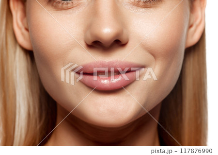 Plump female lips. Lip augmentation. Close-up cropped image of female lower face part with well-kept skin and hydrated lips 117876990