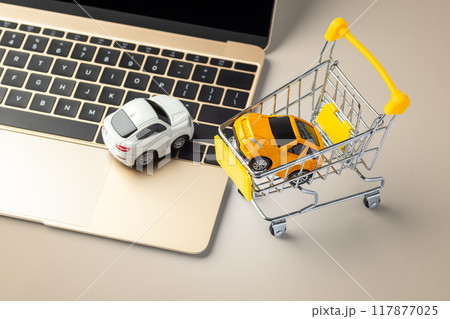 Car toy on laptop with shopping cart on gold background Car toy on laptop with shopping cart on gold background 117877025
