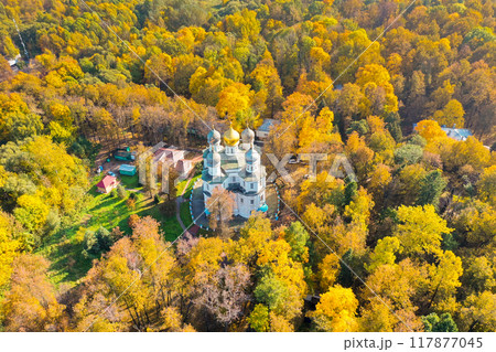 Golden leaves dance around a quaint church nestled in a vibrant autumn forest during a sunny afternoon Golden leaves dance around a quaint church nestled in a vibrant autumn forest during a sunny afternoon 117877045