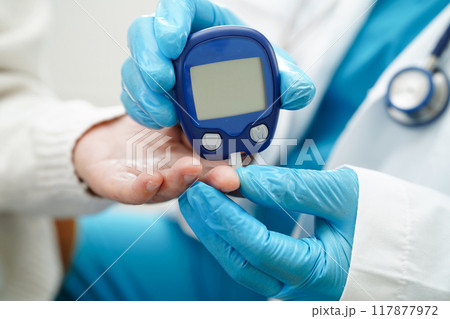 Asian doctor using digital glucose meter for check sample blood sugar level to treatment diabetes. Asian doctor using digital glucose meter for check sample blood sugar level to treatment diabetes. 117877972