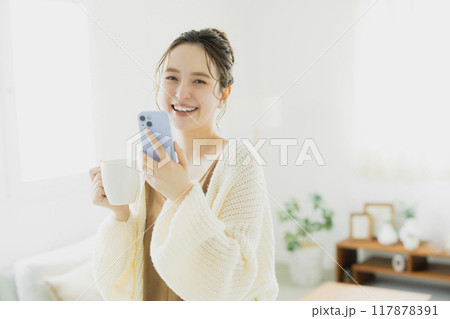 部屋でスマホを見る若い女性 部屋でスマホを見る若い女性 117878391