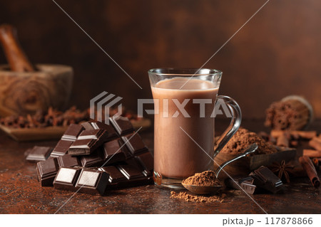 Pieces of bitter chocolate and glass of cocoa drink on a brown table. 117878866
