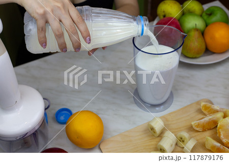 Female hands pouring bottle of milk into measuring cup for blending, making sports drink from fruits and milk with vitamins, healthy homemade milkshake with fresh fruits Female hands pouring bottle of milk into measuring cup for blending, making sports drink from fruits and milk with vitamins, healthy homemade milkshake with fresh fruits 117879176