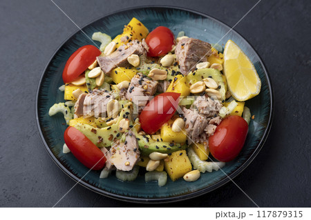 Salad with canned tuna, tomatoes, peanuts, mango, avocado, celery, chili flakes and black sesame. Light summer salad with olive oil and a lemon lobule. Selective focus, close-up, black background. Salad with canned tuna, tomatoes, peanuts, mango, avocado, celery, chili flakes and black sesame. Light summer salad with olive oil and a lemon lobule. Selective focus, close-up, black background. 117879315