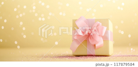 Elegant gift box in pastel color with pink ribbon on sparkling yellow background 117879584
