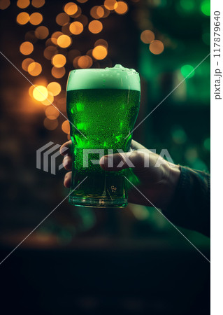 St. Patricks day green beer pint over dark background in mans hand for pub party 117879640