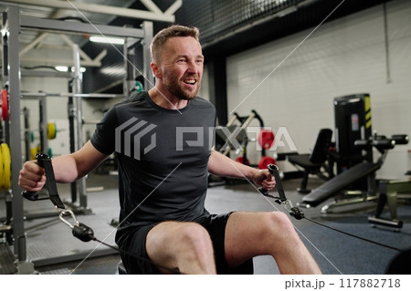 Professional bodybuilder using weight machine to improve muscle 117882718