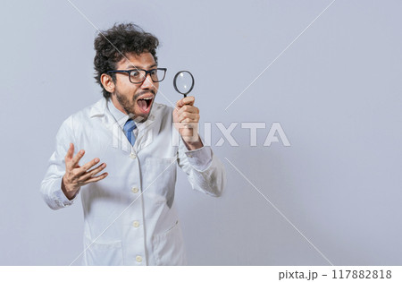 Surprised scientist observing with a magnifying glass to the side. Scientist holding a magnifying glass looking to the side, Man in a white coat with a magnifying glass looking advertisement 117882818