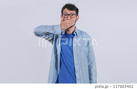 Surprised man covering his mouth on isolated background, Surprised man in glasses covering his mouth, concept of astonished man covering his mouth Surprised man covering his mouth on isolated background, Surprised man in glasses covering his mouth, concept of astonished man covering his mouth 117883402