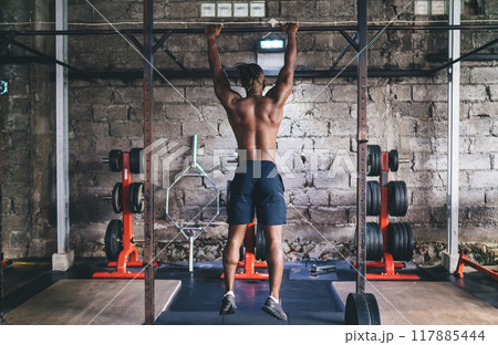 Unrecognizable black man athlete doing abs exercise on horizontal bar 117885444