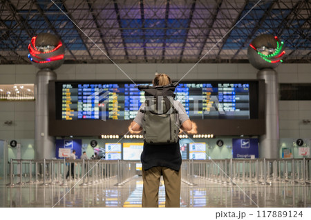 Young Asian woman in international airport looking at flight information board, checking her flight 117889124