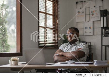 African American businessman working on paperwork, searching for information with laptop at home office African American businessman working on paperwork, searching for information with laptop at home office 117889129