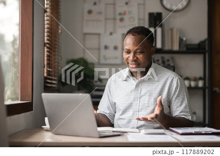 African American businessman working with laptop, online meeting and presenting results via Zoom online. African American businessman working with laptop, online meeting and presenting results via Zoom online. 117889202