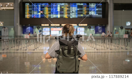 Young Asian woman in international airport looking at flight information board, checking her flight Young Asian woman in international airport looking at flight information board, checking her flight 117889214