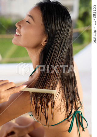 Hair Care. Woman Smiling While Combing Wet Hair Outdoors for Healthy Hair Care Routine 117893155