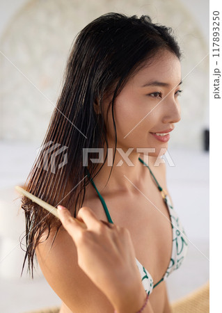 Hair Health. Woman Combing Wet Hair for Healthy Hair Care Routine in Relaxing Setting Hair Health. Woman Combing Wet Hair for Healthy Hair Care Routine in Relaxing Setting 117893250