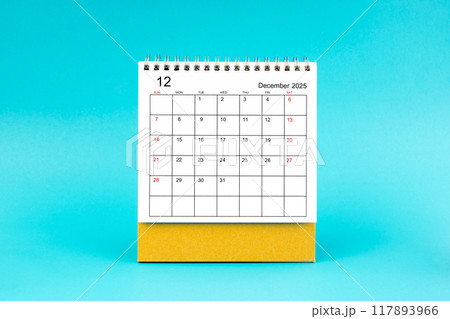 December 2025 desk calendar on blue background. 117893966