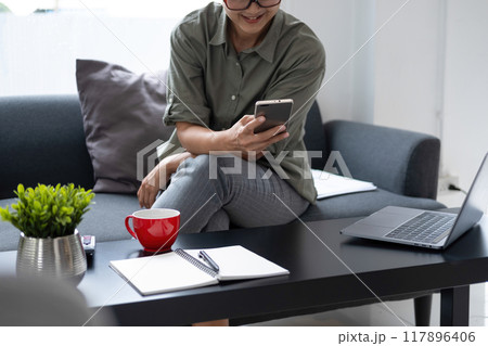 Businesswoman sitting at desk on couch in workplace or Businesswoman sitting at desk on couch in workplace or 117896406