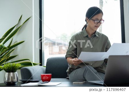Businesswoman sitting at desk on couch in workplace or 117896407