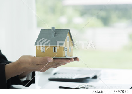 Real estate agent handing property keys to customer. 117897070