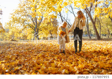Stylish mother and daughter enjoy the autumn park. Family on a walk. Childhood, walks, rest. 117897955