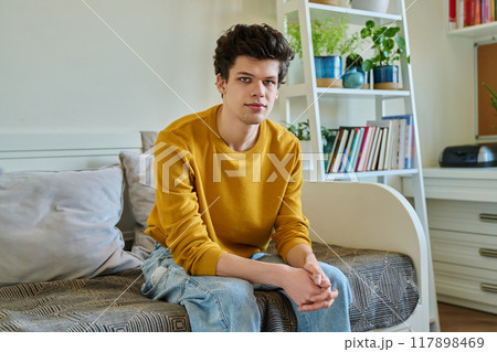 Portrait of handsome guy looking at camera, sitting on couch at home Portrait of handsome guy looking at camera, sitting on couch at home 117898469