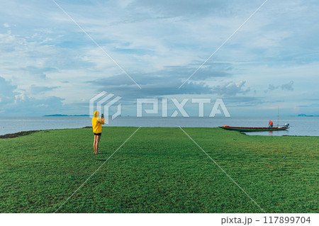 Woman in yellow hood walking on the wetland, Thale Noi, Thailand. Woman in yellow hood walking on the wetland, Thale Noi, Thailand. 117899704