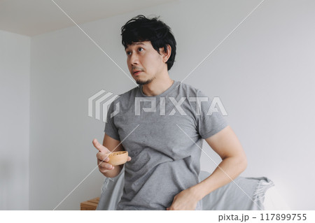Man eating snacks peanuts in the house to increase his protein and magnesium. Man eating snacks peanuts in the house to increase his protein and magnesium. 117899755