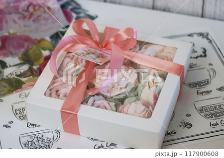 A box of homemade marshmallows. Tied with a ribbon. The tag has the inscription in Russian From the bottom of my heart. Flowers made of marshmallow. 117900608