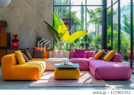 Modern living room with colorful sofas and large windows overlooking a tropical garden. Vibrant colors. 117901552