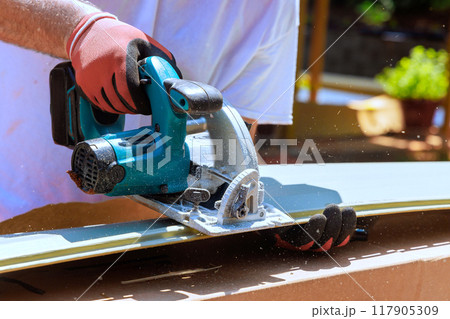 During construction facade of craftsman cuts vinyl siding panel to desired size before installing it During construction facade of craftsman cuts vinyl siding panel to desired size before installing it 117905309