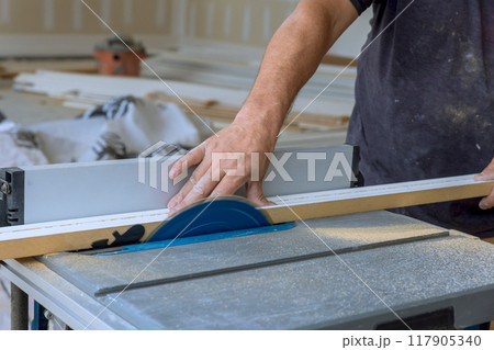 Electrically powered table saws are used to cut wood molding filler Electrically powered table saws are used to cut wood molding filler 117905340
