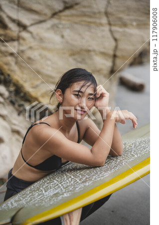 岩場でサーフボードを持っている若い女性 岩場でサーフボードを持っている若い女性 117906008