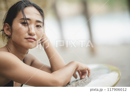 岩場でサーフボードを持っている若い女性 岩場でサーフボードを持っている若い女性 117906012